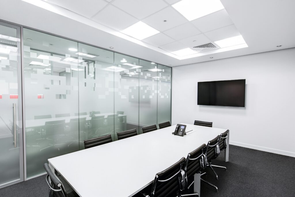 Sleek, minimalist conference room with glass walls, long table, and office chairs.